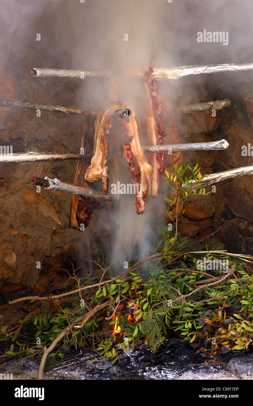 Preparazione di 'syglino' (noto anche come "pasto'=affumicato di maiale) una famosa prelibatezza locale e salsicce in mani, Messinia Grecia. Foto Stock