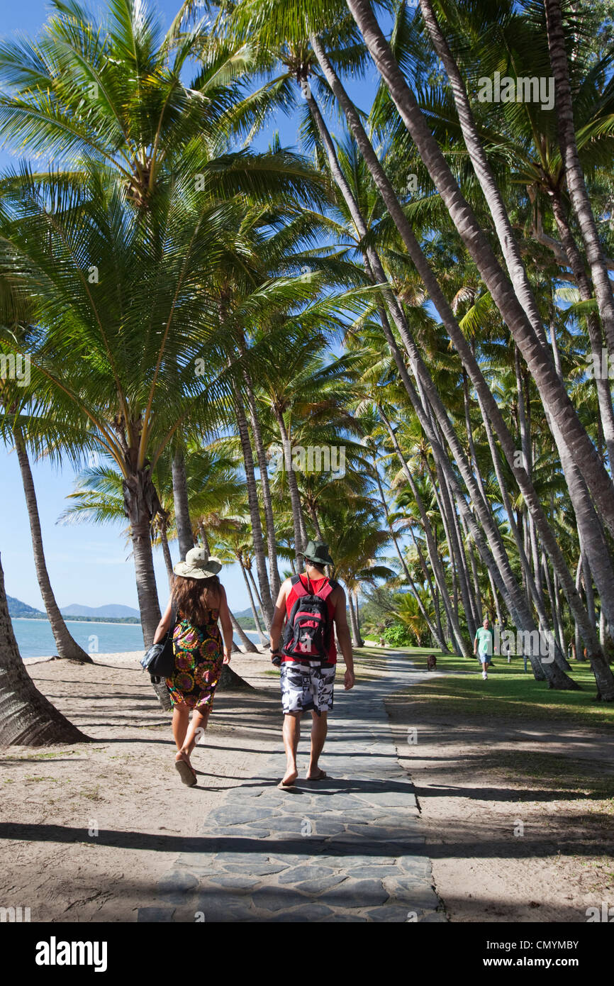 I turisti a piedi attraverso palme da cocco sulla spiaggia. Palm Cove, Cairns, Queensland, Australia Foto Stock