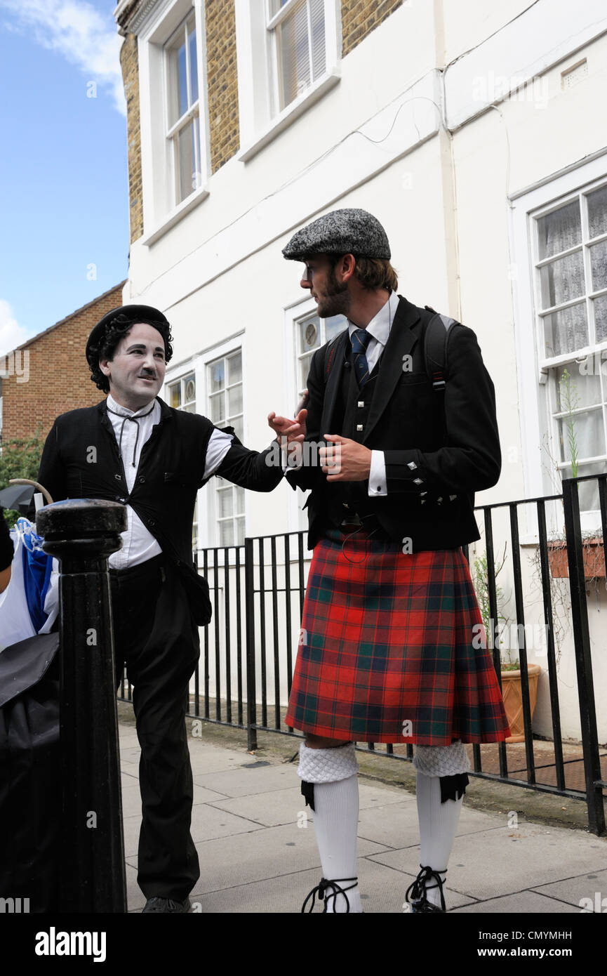 Regno Unito, Londra, Mercato di Portobello Road, mime street performer vestito come Charlie Chaplin ospeaking con un uomo scozzese Foto Stock