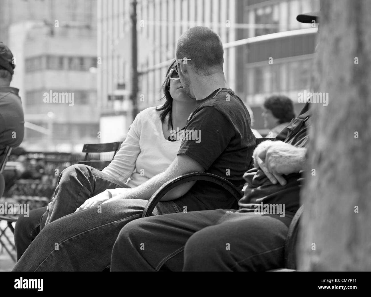 Un giovane kiss mentre vi rilassate nel Bryant Park di New York City. Foto Stock