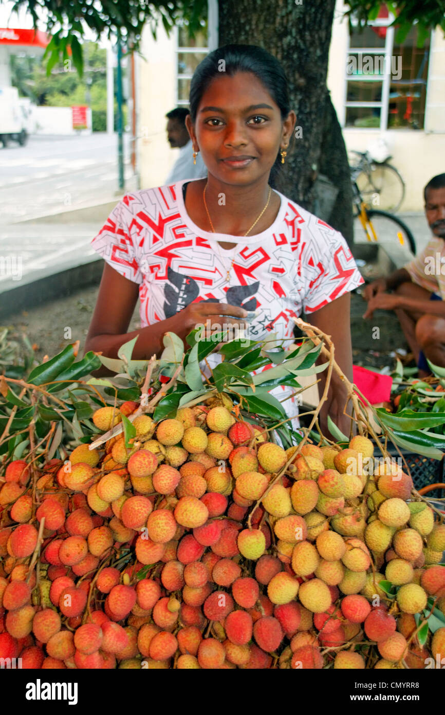 Ragazza indiana con Lischis frutta stallo, Maurizio, Africa Foto Stock