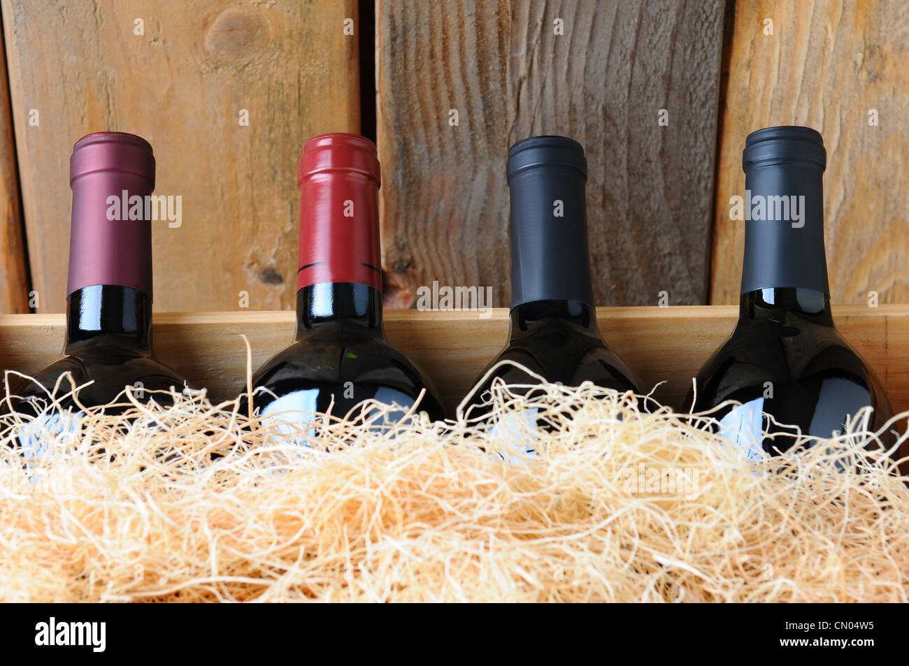 Primo piano di quattro diverse bottiglie di vino in una cassa di legno con paglia e il materiale di imballaggio. Foto Stock