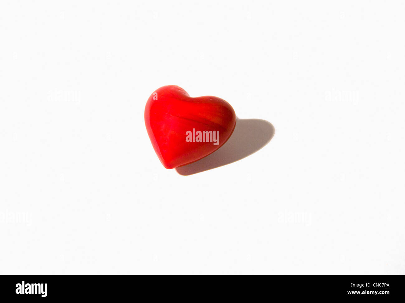 Cuore, cuore rosso pietra sagomata contro uno sfondo bianco. Foto Stock