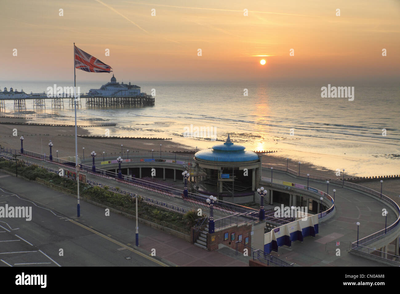 La britannica Union Jack flag battenti una bandiera pole con Eastbourne Pier in background, East Sussex, Inghilterra. Foto Stock