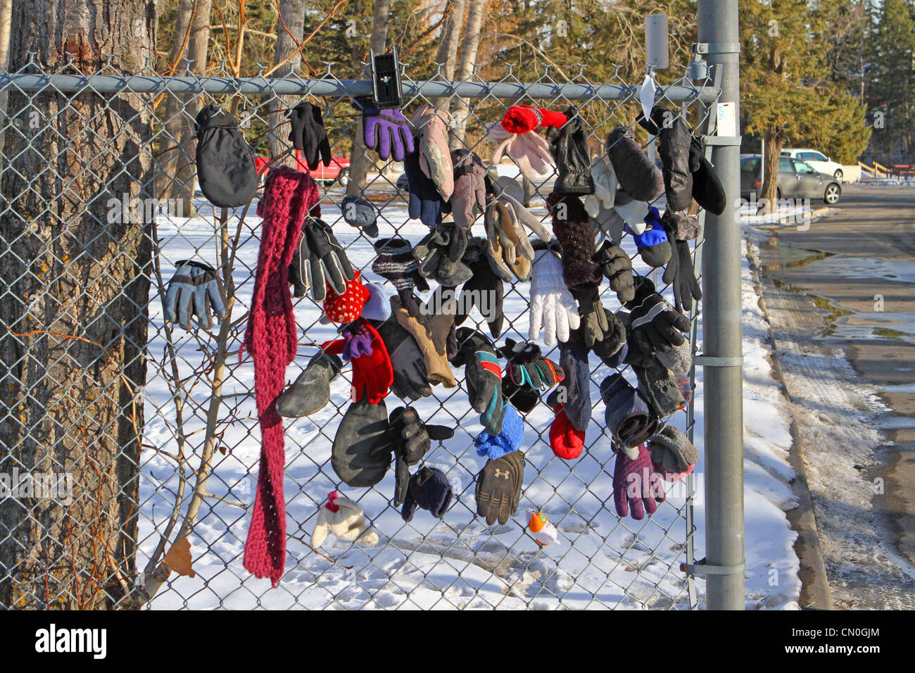 Perso i guanti e cappelli da un parco percorso attaccato a una catena di recinzione di collegamento Foto Stock