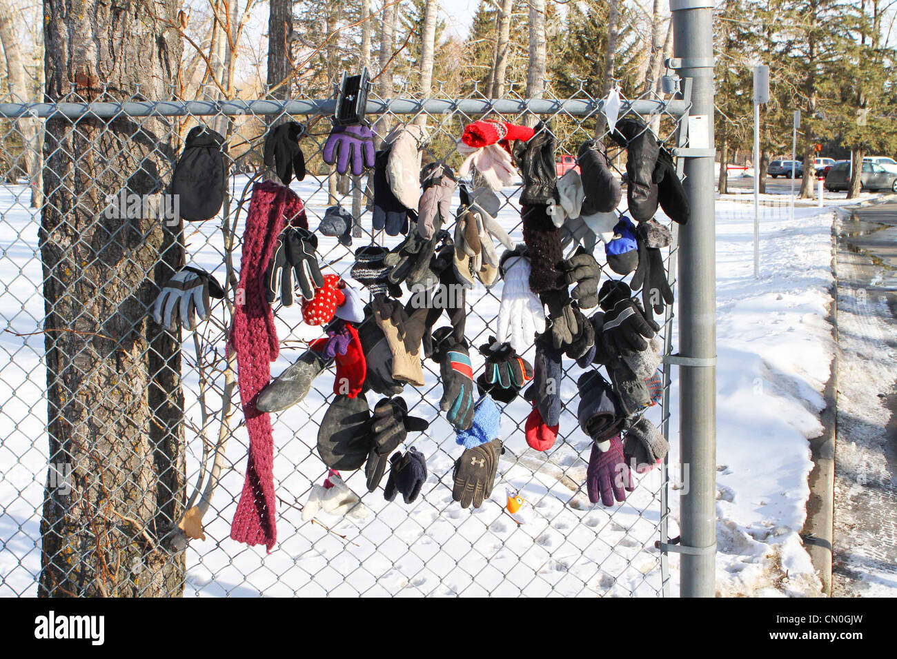 Perso i guanti e cappelli da un parco percorso attaccato a una catena di recinzione di collegamento Foto Stock