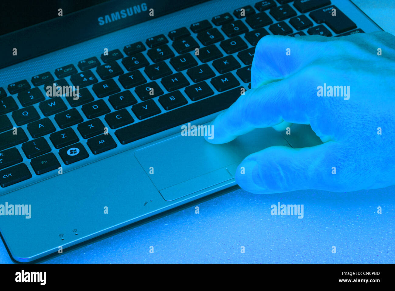Un mans mano utilizzando un netbook con oltre tutto il cast di colore blu Foto Stock