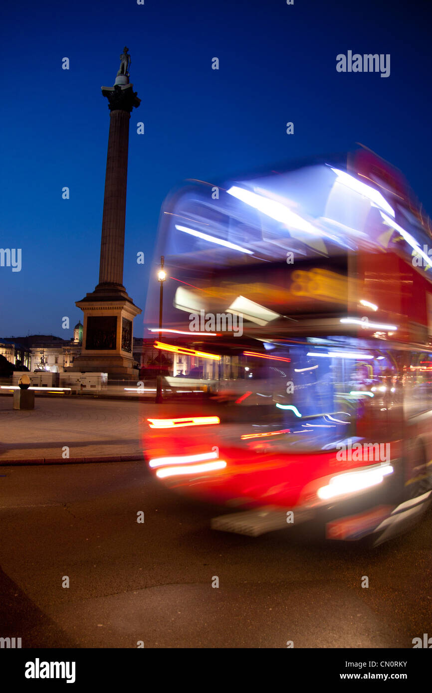 Nelson la colonna e Trafalgar Square a crepuscolo / notte con sfocato red bus londinese passando Londra Inghilterra REGNO UNITO Foto Stock