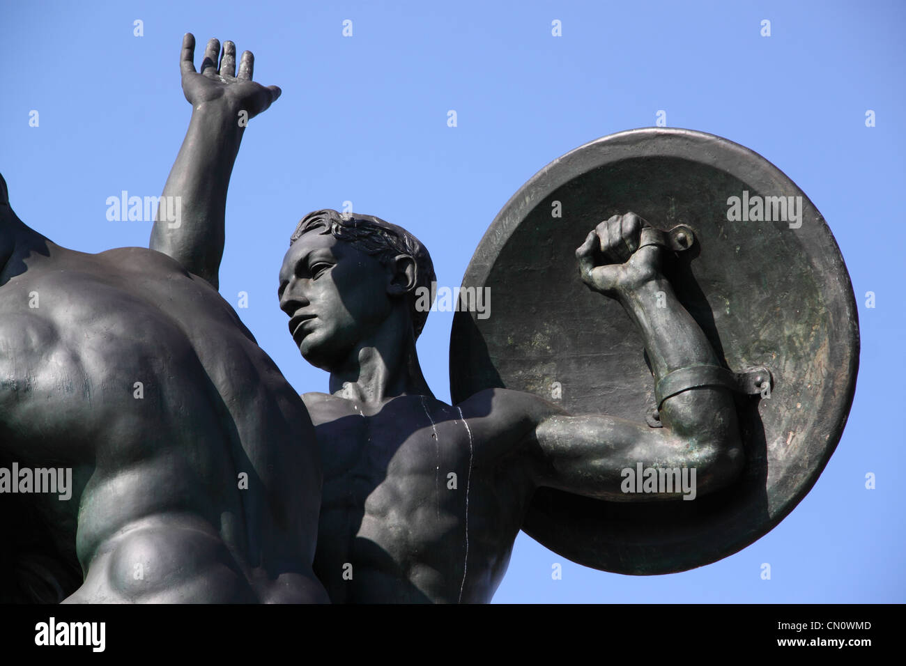 Una statua di bronzo di un giovane soldato con uno scudo, su un cielo blu sullo sfondo Foto Stock