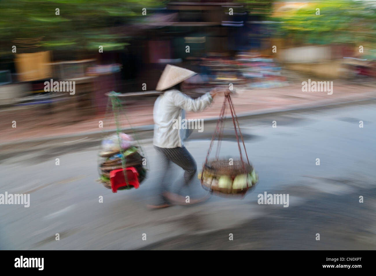 Donna con cappello conico e la spalla polo sulla strada, Hoi An, Vietnam Foto Stock