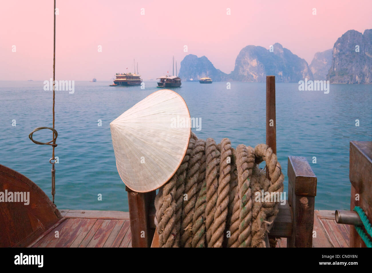 Cappello conico sulla barca di posta indesiderata e del carso isole nella baia di Halong, sito Patrimonio Mondiale dell'UNESCO, la baia di Ha Long, Vietnam Foto Stock