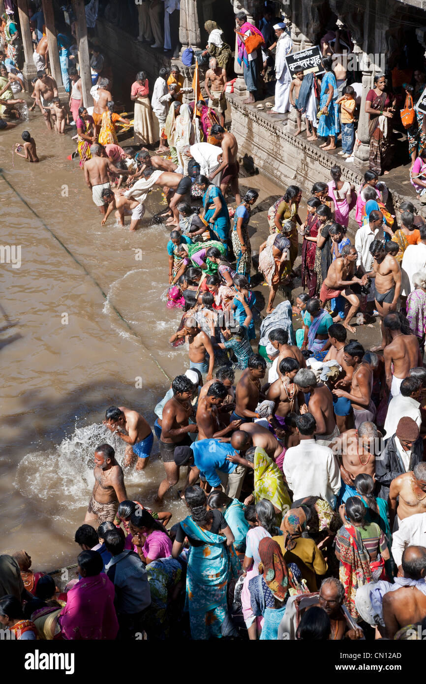 Pellegrini indù la balneazione in acqua sacra serbatoio di Kushavarta (la sorgente del fiume Godavari). Trimbakeshwar. India Foto Stock