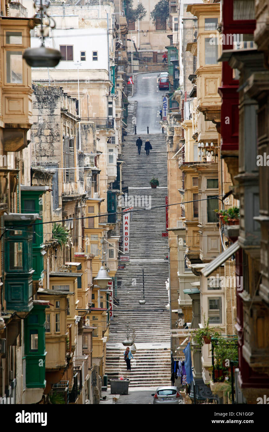 Scena di strada coperta con balconi in legno e i voli di lunga durata di scale su una collina a La Valletta, Malta Foto Stock