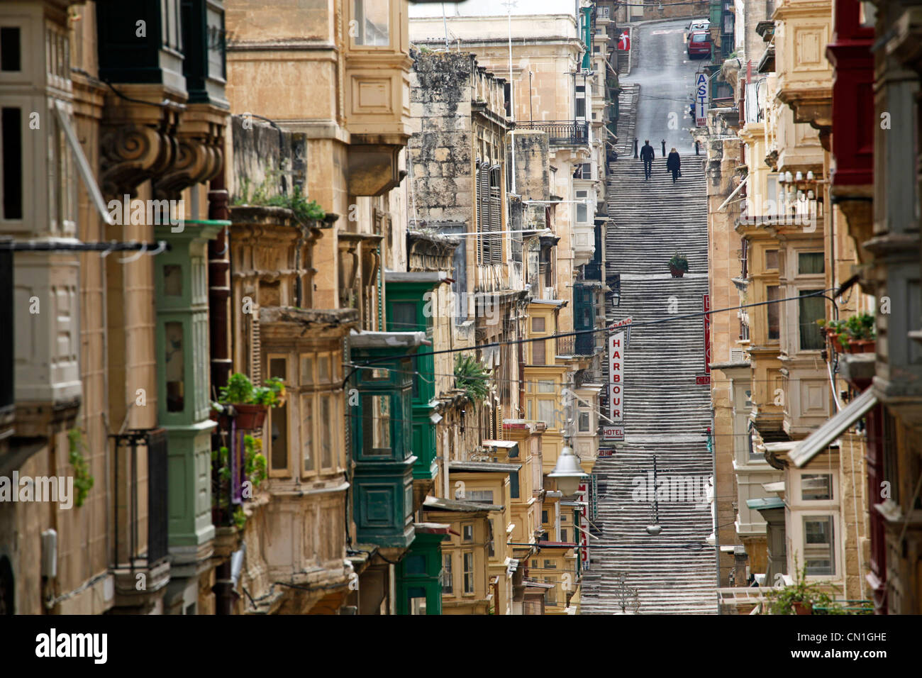 Scena di strada coperta con balconi in legno e i voli di lunga durata di scale su una collina a La Valletta, Malta Foto Stock