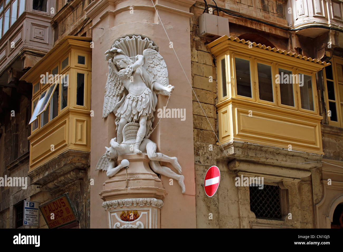 Fregio statua di San Michele e il diavolo su edifici con terrazze coperte a La Valletta, Malta Foto Stock