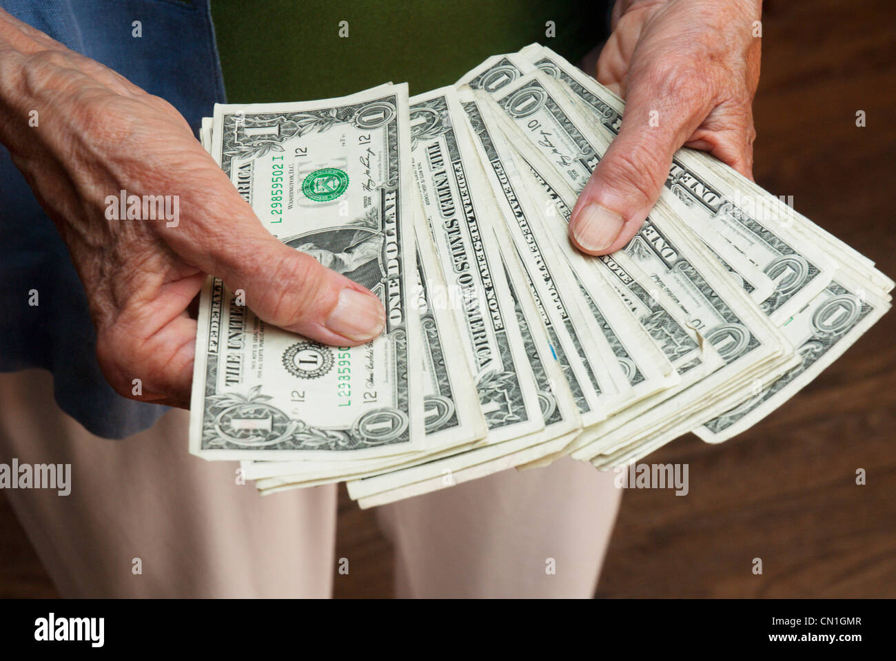 Donna anziana le mani tenendo le fatture del dollaro Foto Stock