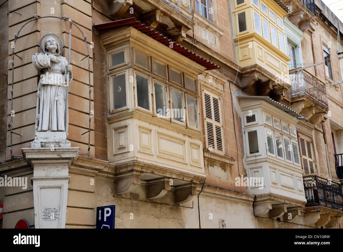 Statua di San Francesco e coperto balconi in legno in strada a La Valletta, Malta Foto Stock