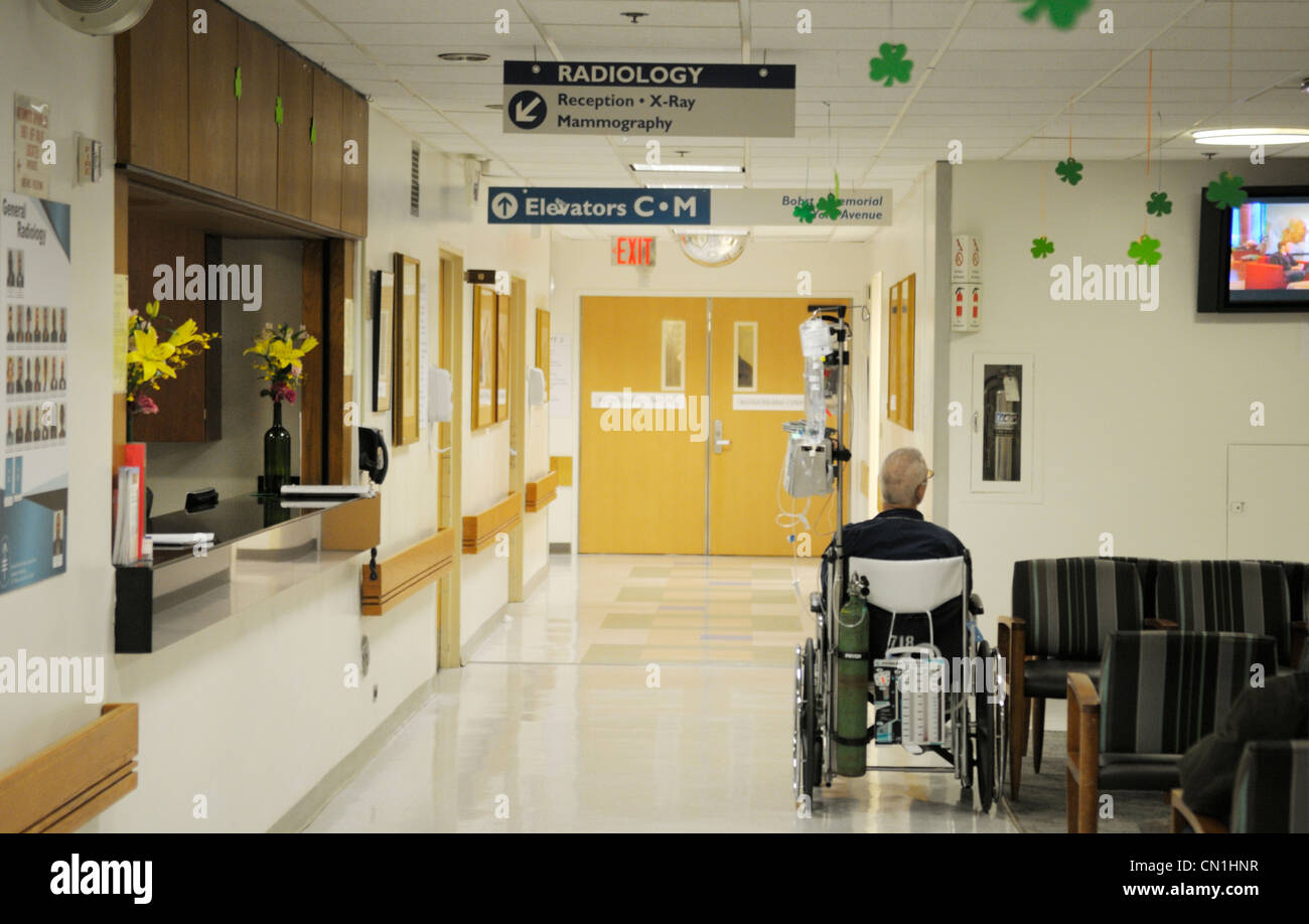 La radiologia ospedale area di attesa con un paziente anziano in una sedia a rotelle Foto Stock