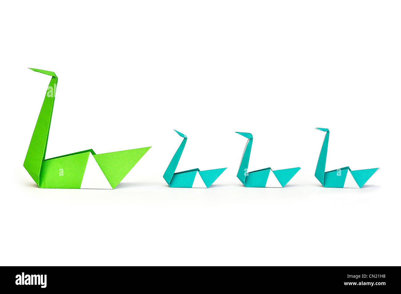 Origami Libro Verde Swan che conduce a tre piccoli baby cigni Foto Stock