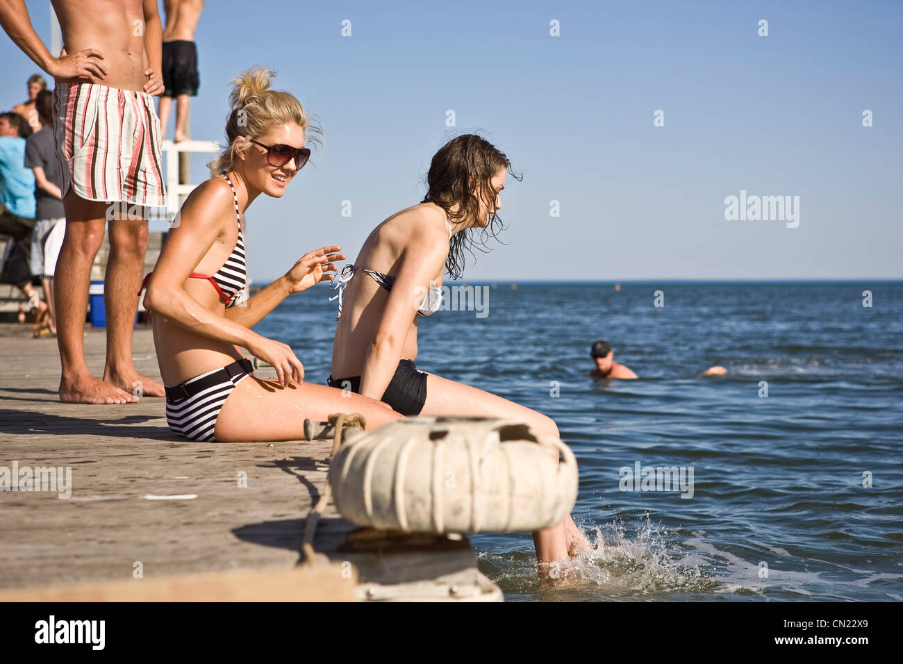 Due giovani donne seduta sul bordo del molo Foto Stock