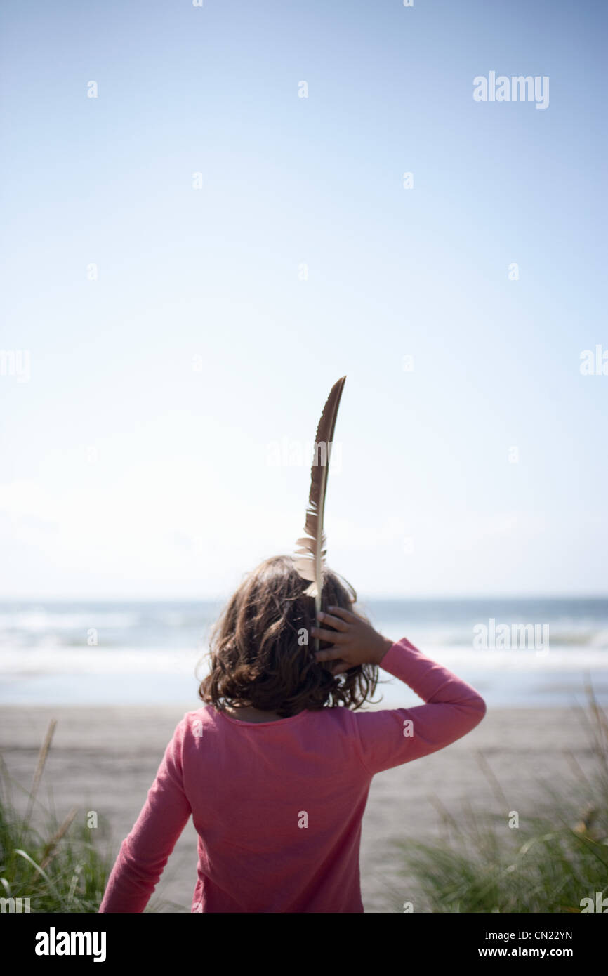 Vista posteriore della ragazza alla spiaggia con piuma Foto Stock