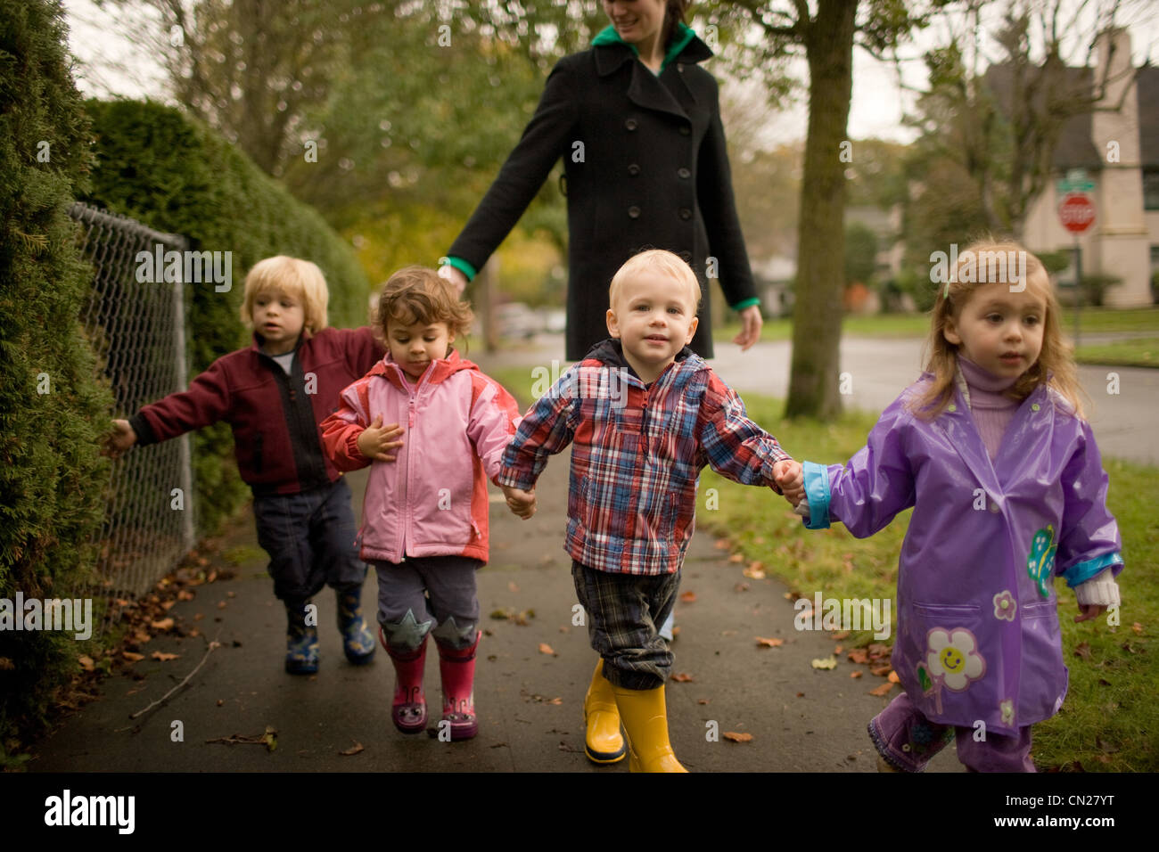 Donna con quattro bambini camminando lungo il marciapiede Foto Stock