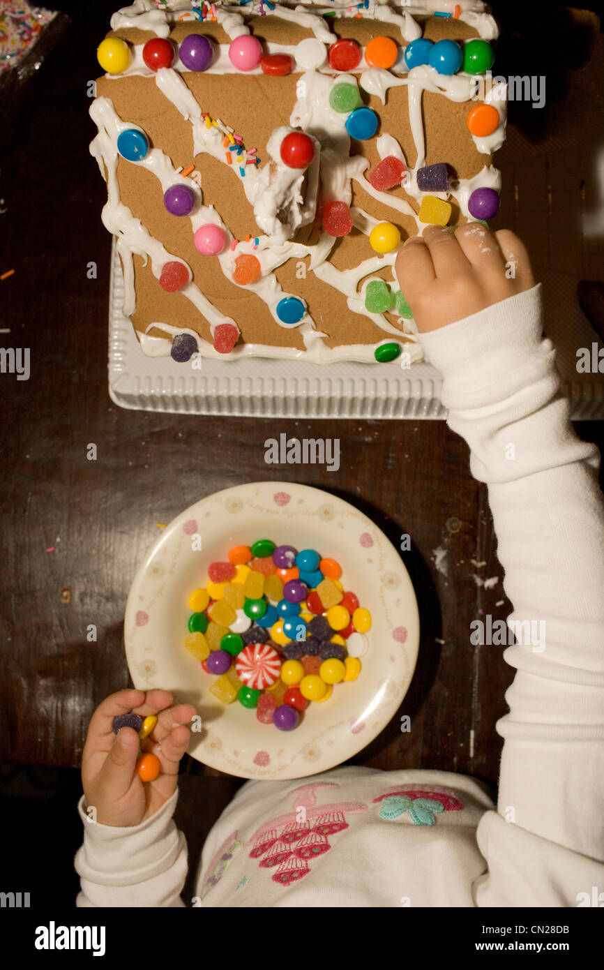 Ragazza giovane decorare gingerbread house Foto Stock