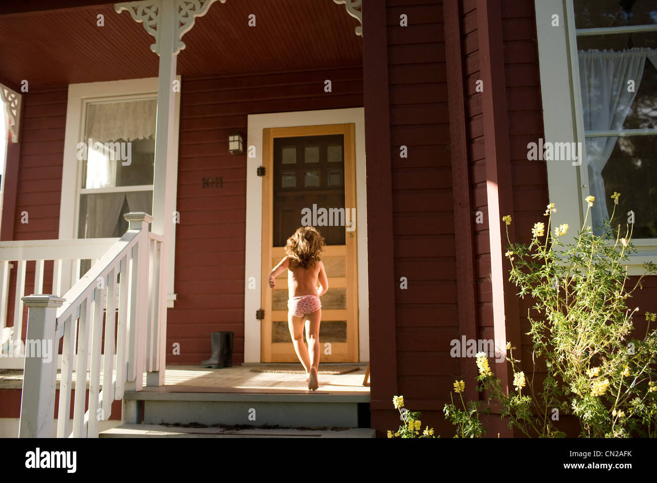 Giovane ragazza che corre verso la porta anteriore Foto Stock