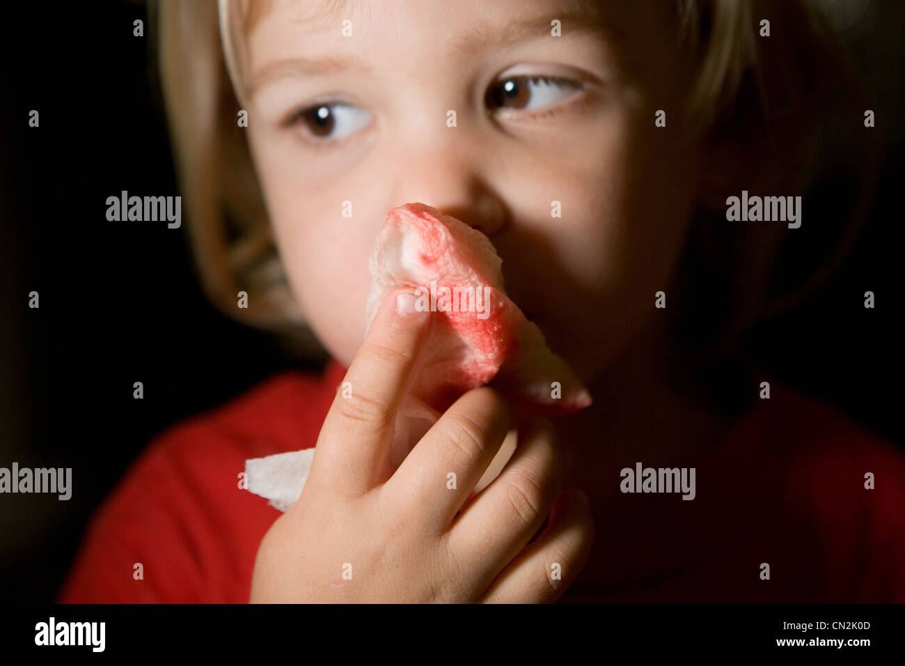 Ragazzo holding macchiato di sangue il tessuto carta al di sopra del naso Foto Stock