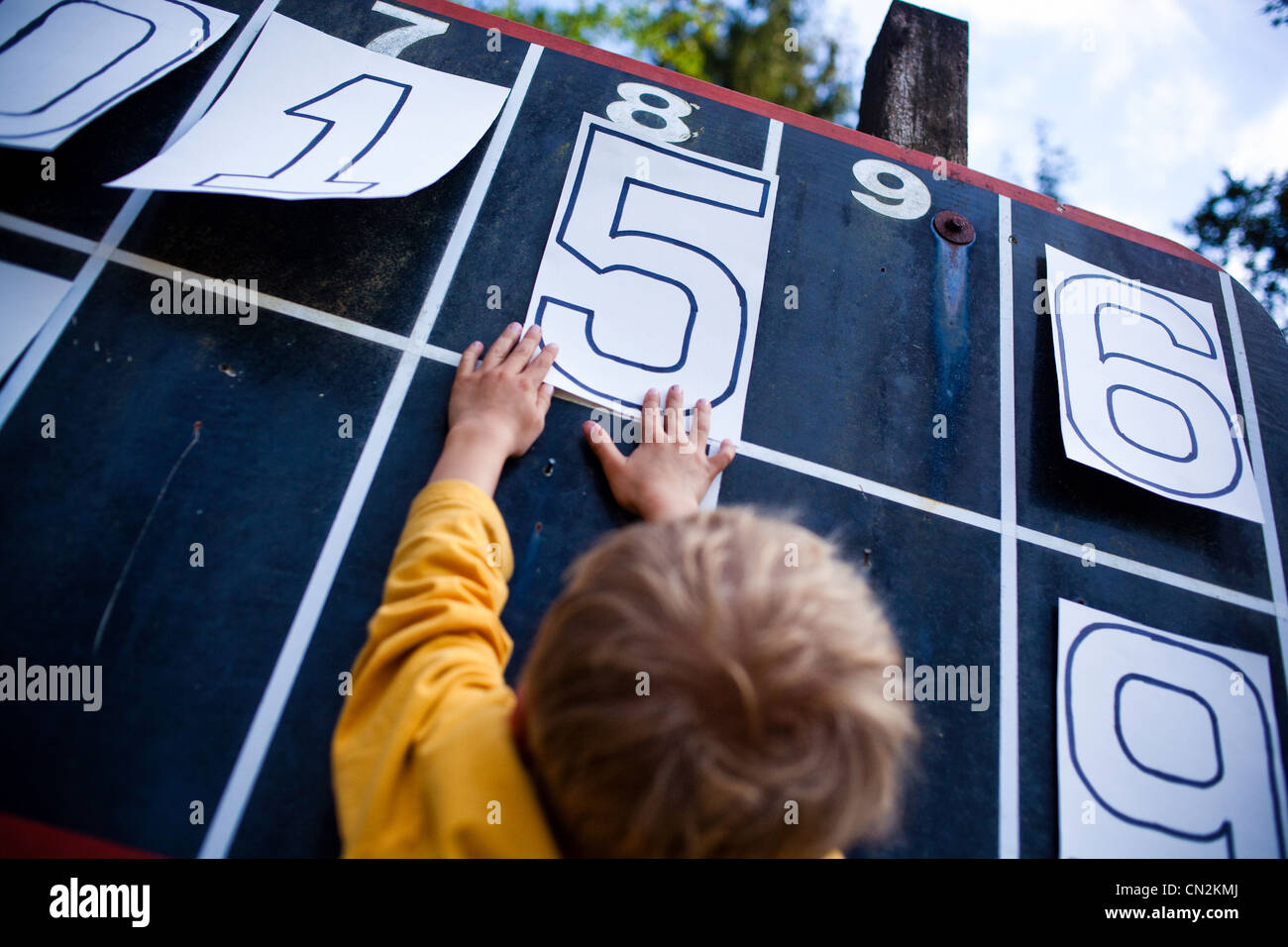 Giovane ragazzo giocando con i numeri sul tabellone Foto Stock