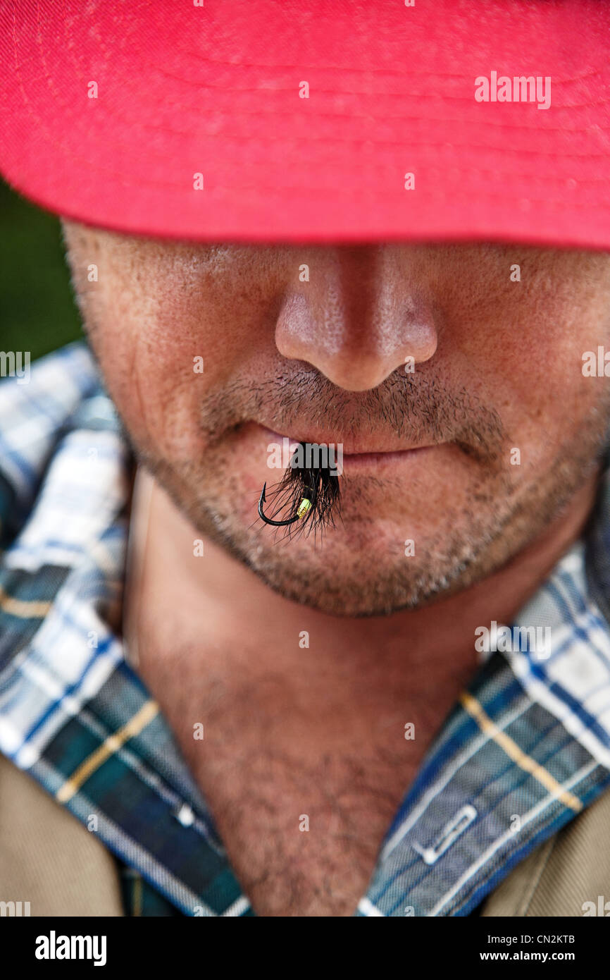 Uomo con la pesca con la mosca esca in bocca Foto Stock