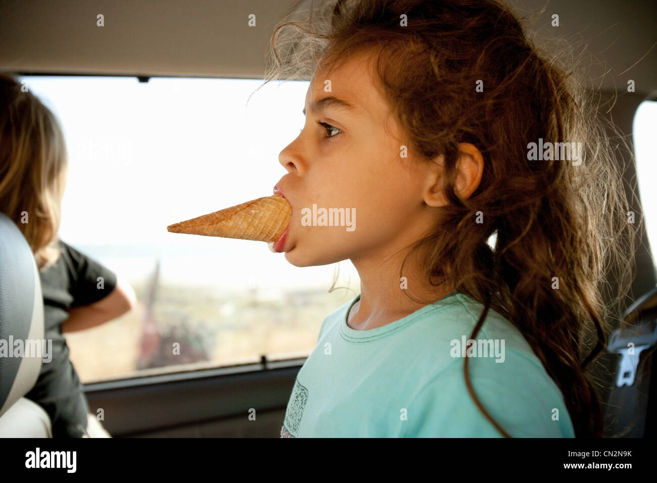 Ragazza giovane con cono gelato in bocca Foto Stock