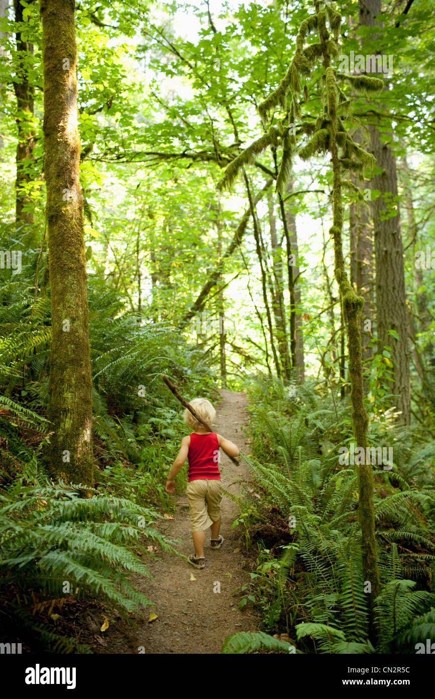 Ragazzo giovane a piedi lungo una strada forestale Foto Stock