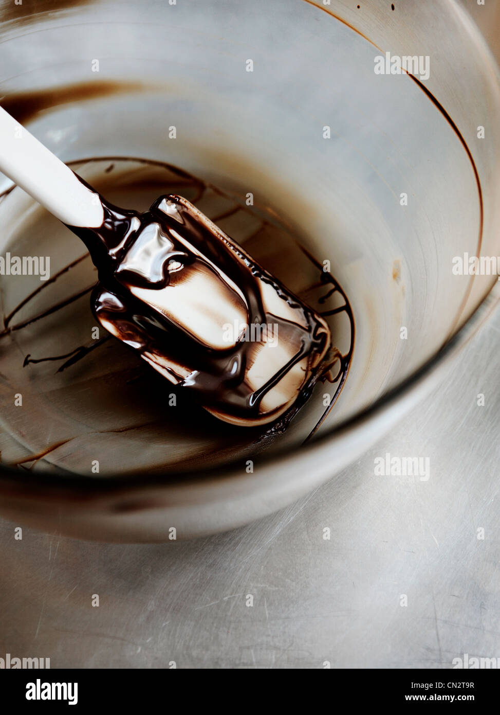 Cioccolato fondente fuso nel recipiente di miscelazione con la spatola Foto Stock