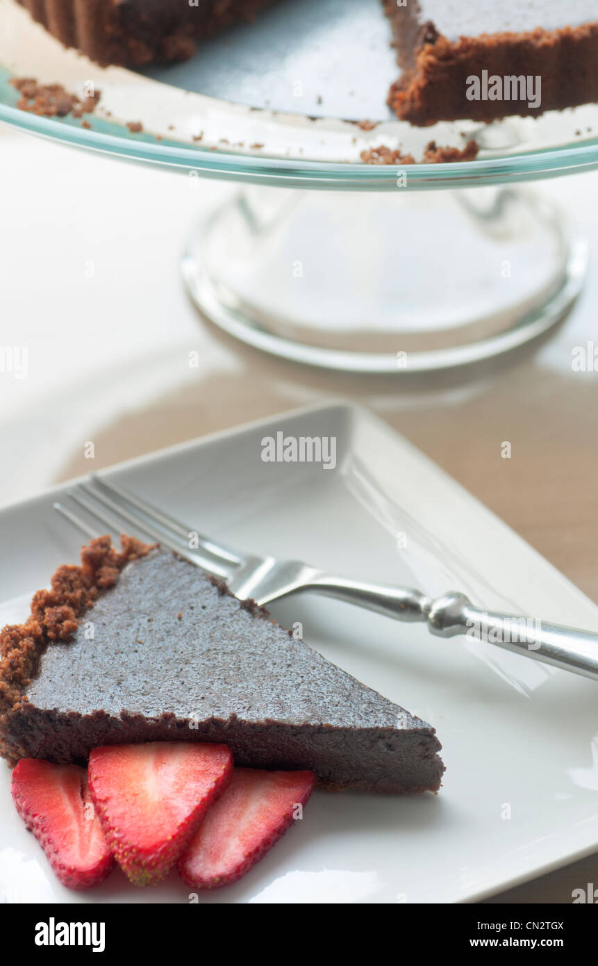 Fetta della ricca torta al cioccolato con zenzero crosta di biscotti e fragole fresche Foto Stock