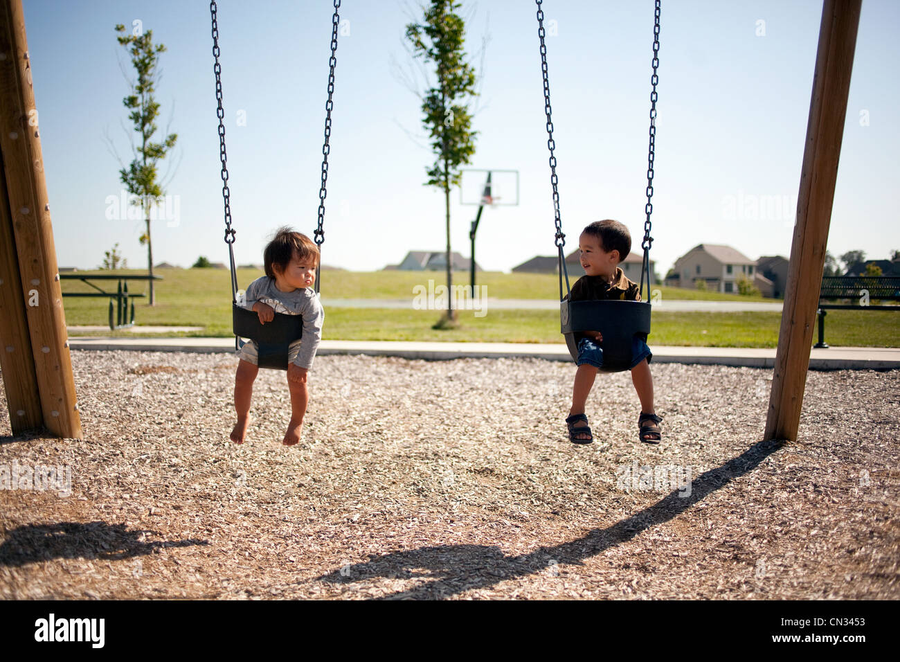 Due ragazzi in seduta altalene Foto Stock