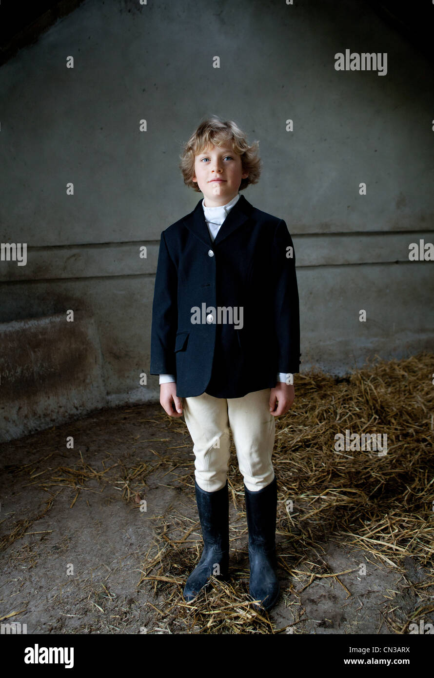 Ragazzo che sta a cavallo vestiti in stabile Foto Stock