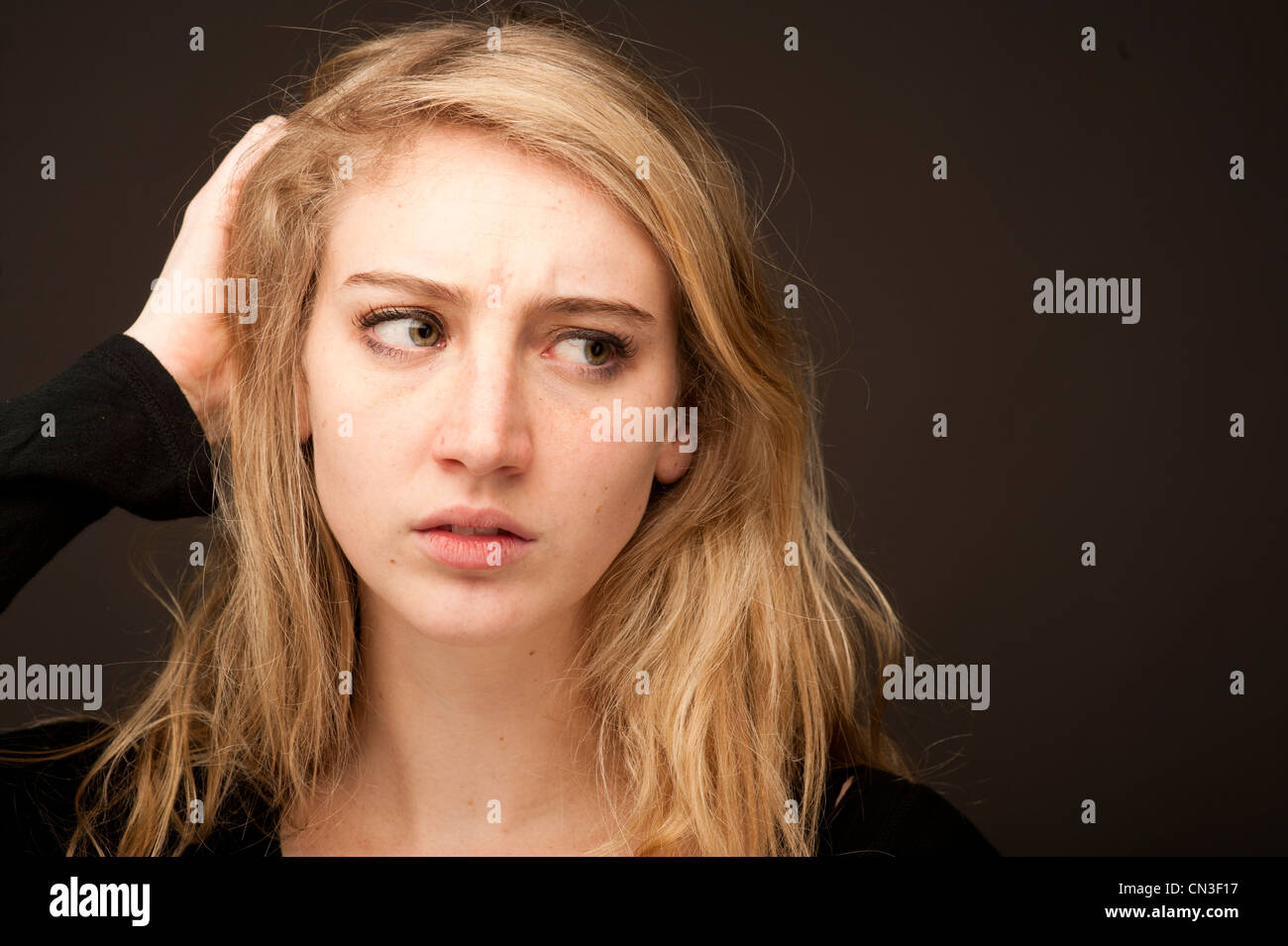 Un giovane biondo 19 enne ragazza adolescente guardando preoccupato confuso interessati di graffiare la sua testa Foto Stock