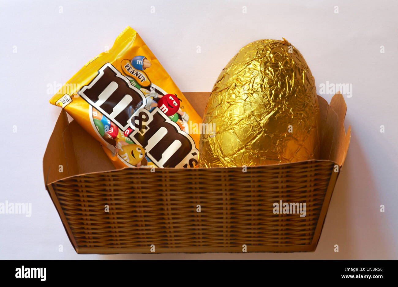 M&m's uovo di pasqua e il pacchetto di arachide m&m's in cartone cestello isolato su sfondo bianco - Pronto per la Pasqua Foto Stock