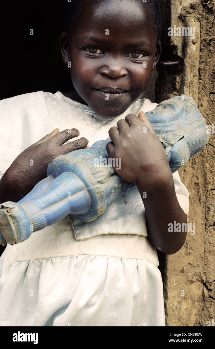 Ragazza africana in abito bianco tiene la bambola blu polverosa Foto Stock