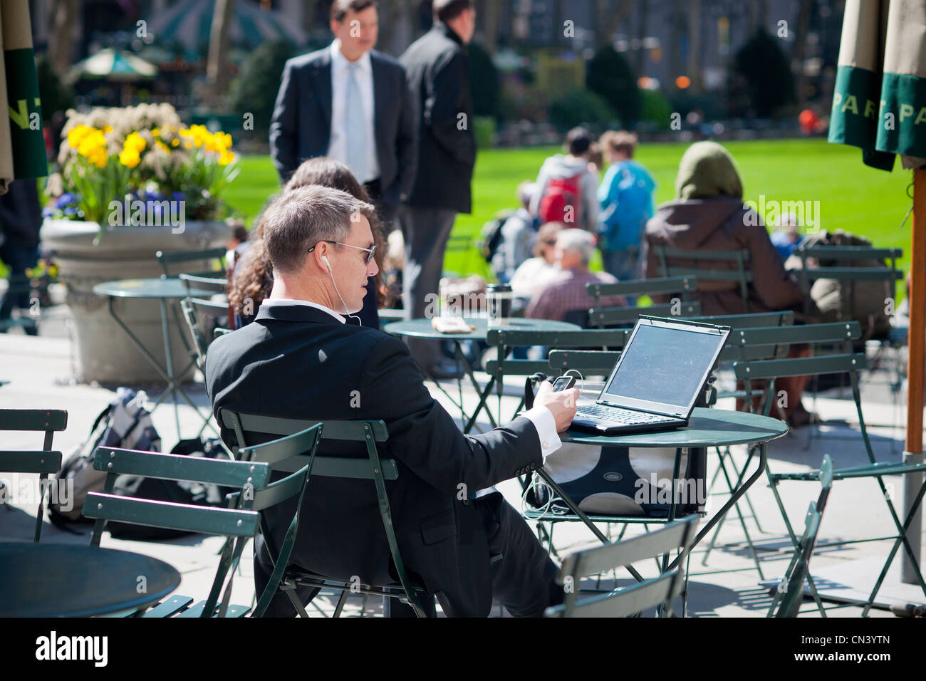 Un imprenditore con il suo computer portatile e telefono cellulare in Bryant Park di New York il Giovedì, Giugno 9, 2011. Foto Stock