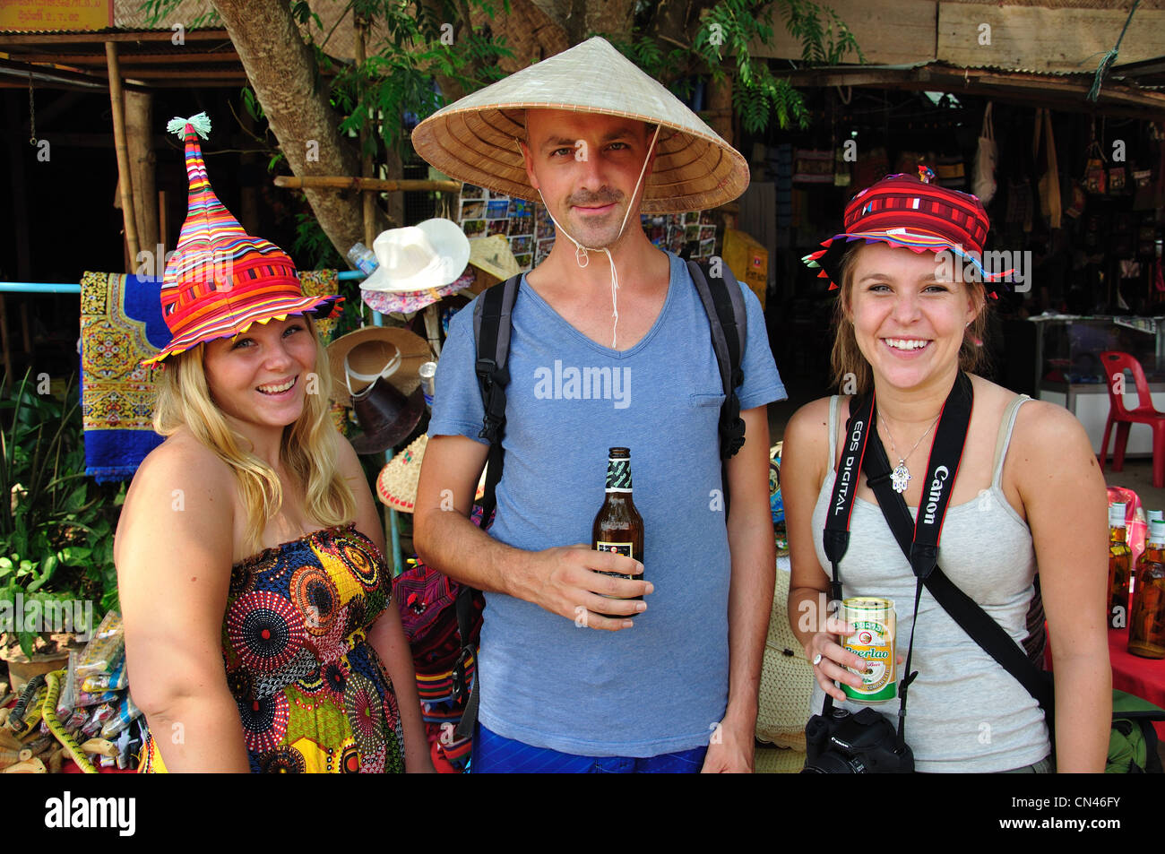 Gruppo turistico indossando cappelli laotiani in mercato all'aperto, Don Sae, Pak Tha Regione, Provincia Bokèo, Laos Foto Stock