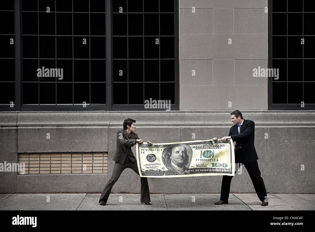 L uomo e la donna stanno lottando per la grande $100 bill Foto Stock