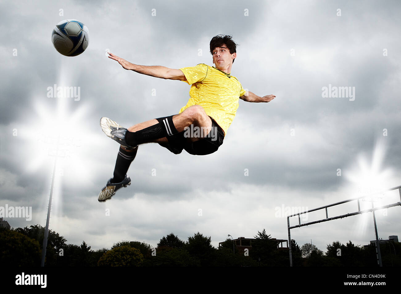 Giocatore di calcio saltando a calciare la sfera Foto Stock