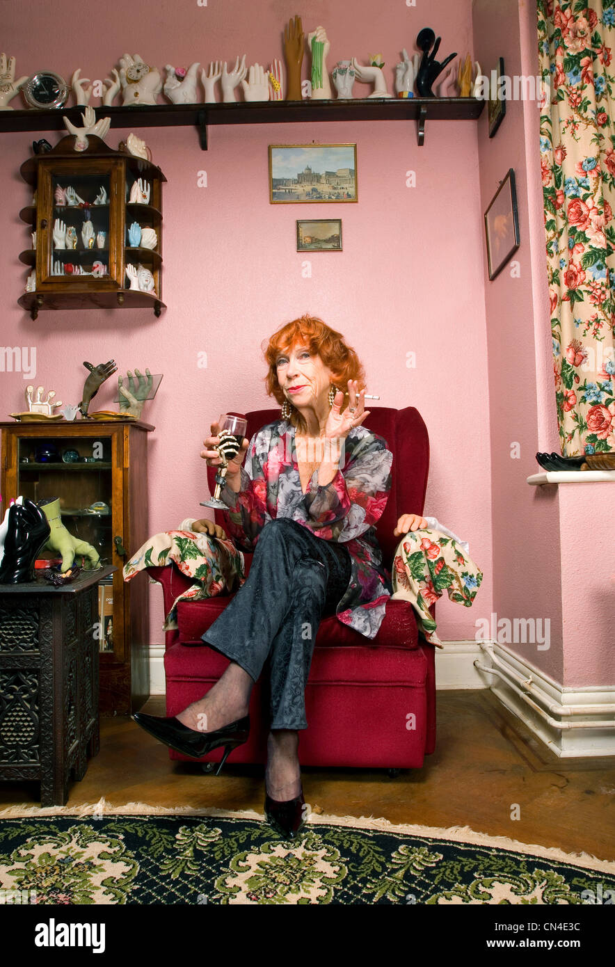 Senior donna in salotto con il vino e la sigaretta, sorridente Foto Stock