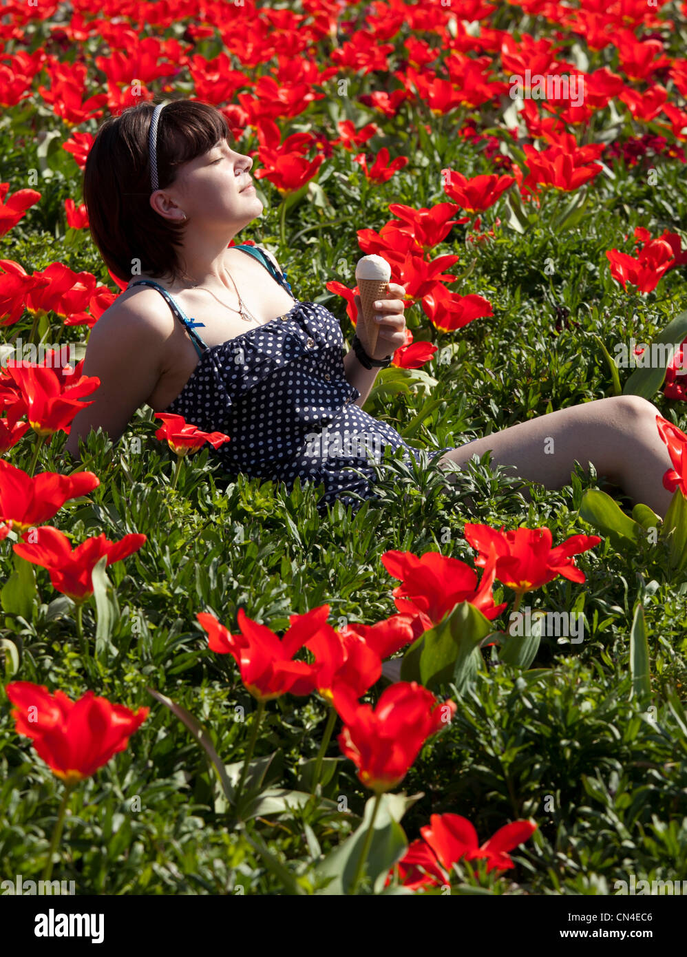 Una ragazza si trova in un mare di fiori nel centro di Stratford upon Avon su un insolitamente caldo giorno di marzo. Foto Stock
