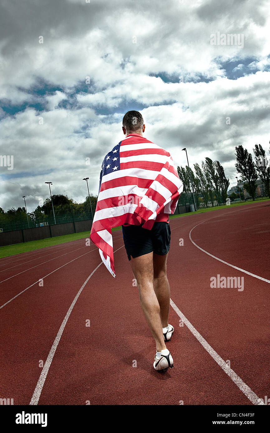 Sprinter in esecuzione con noi bandiera su sportstrack Foto Stock