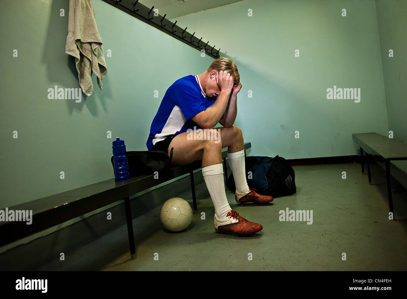 Giocatore di calcio in spogliatoio con testa in mani Foto Stock