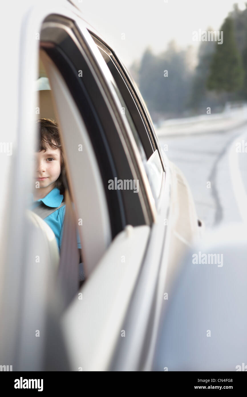 Ragazzo seduto nel sedile posteriore di una macchina Foto Stock