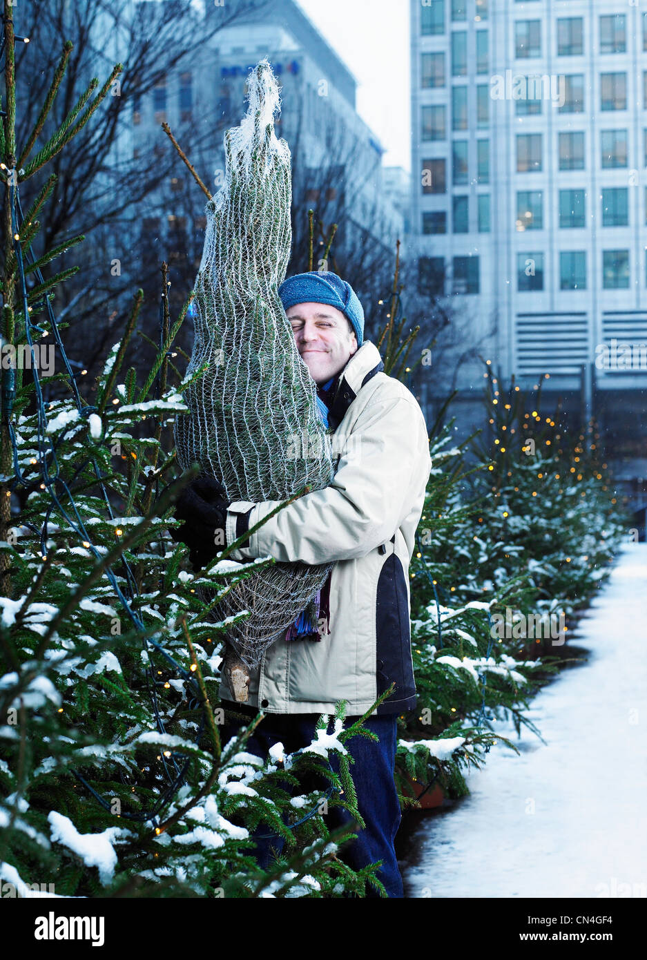 Uomo che abbraccia un albero di Natale Foto Stock